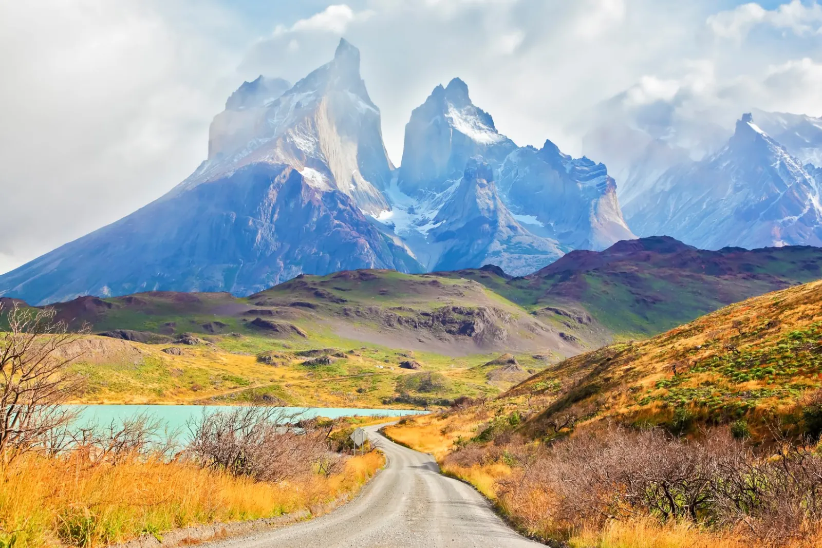 Gravel road through autumn steppe toward the Cuernos del Paine
