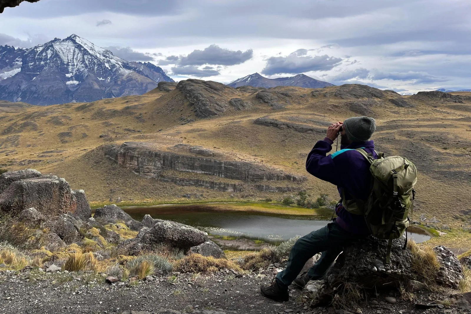 Hiker with binoculars scanning the hills on the Miradores trek