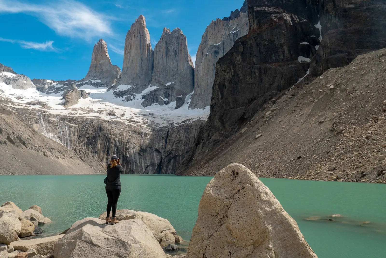 Hiker on a boulder beside the Base Torres lagoon