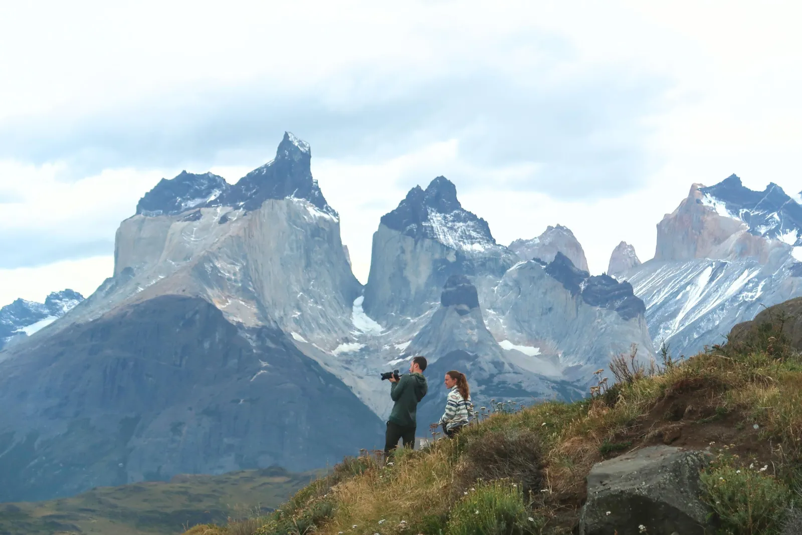 Visitors photographing the Cuernos del Paine from a hillside
