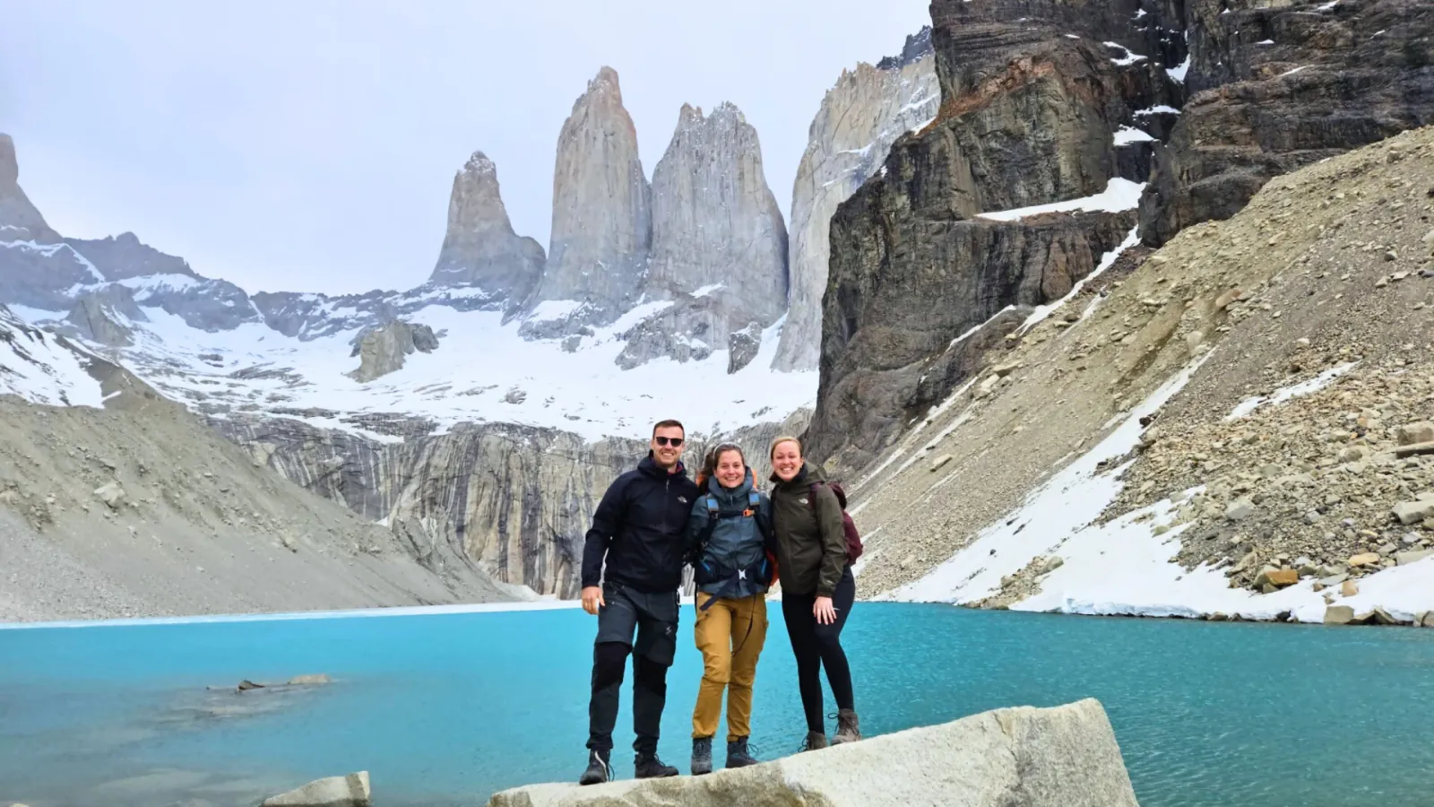 Three hikers on a rock in front of the towers