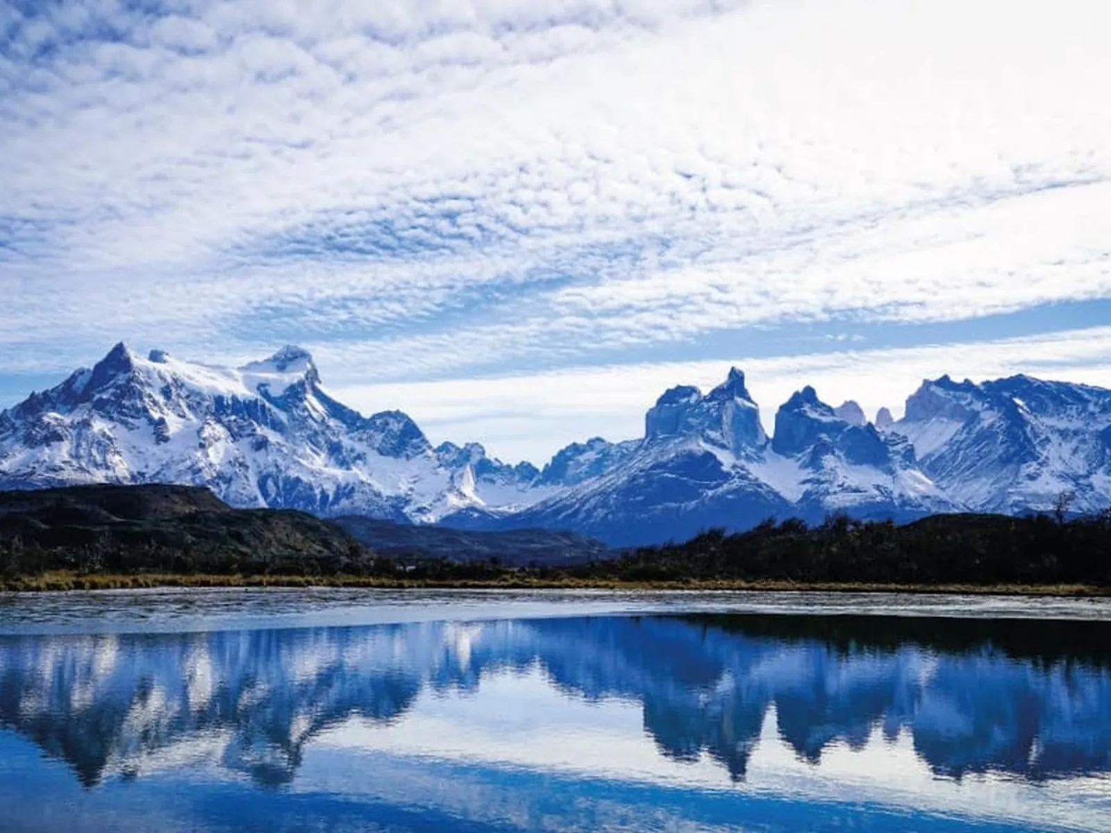 The Paine Massif reflected in a lake under high cloud